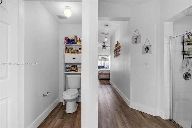 full bath featuring baseboards, visible vents, tiled shower, toilet, and wood finished floors