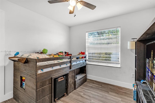 bedroom featuring light wood finished floors, a ceiling fan, and baseboards