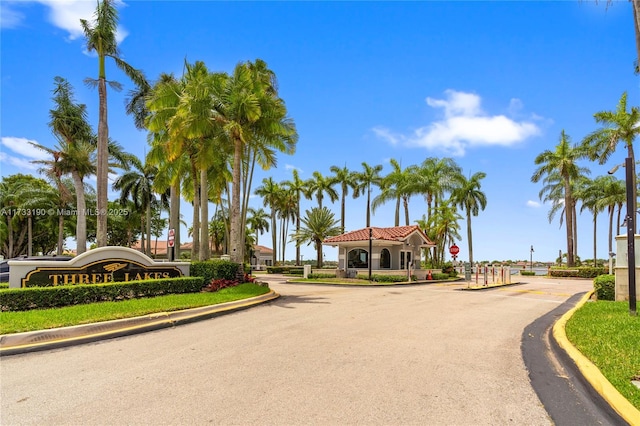 view of road with curbs, a gated entry, and traffic signs