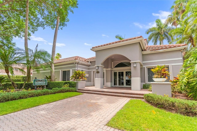 view of front of home with stucco siding, a tiled roof, and french doors