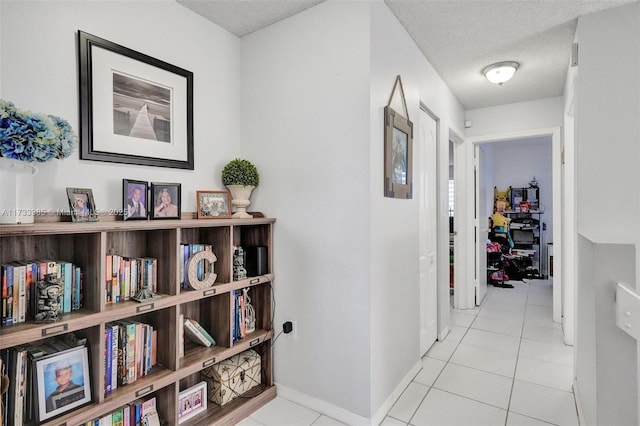 corridor with baseboards, a textured ceiling, and light tile patterned flooring