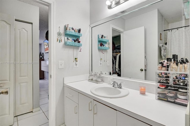 bathroom with a spacious closet, tile patterned flooring, vanity, and a shower with curtain