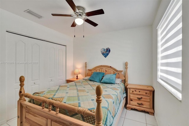 bedroom with a closet, light tile patterned flooring, visible vents, and a ceiling fan