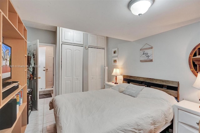 bedroom with light tile patterned floors and two closets