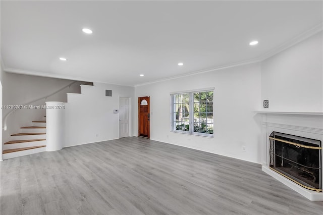 unfurnished living room featuring ornamental molding and light wood-type flooring