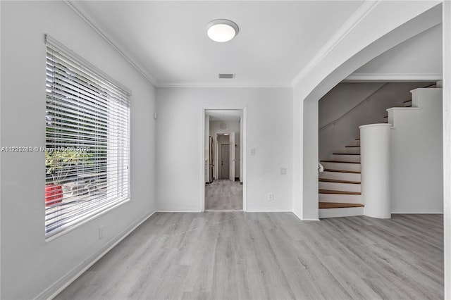 empty room with ornamental molding and light wood-type flooring