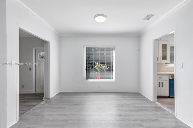 empty room featuring crown molding and light hardwood / wood-style flooring