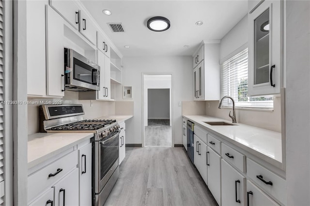 kitchen featuring light wood-type flooring, stainless steel appliances, sink, and white cabinets