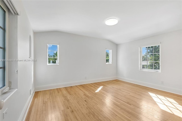 empty room featuring vaulted ceiling and light hardwood / wood-style floors