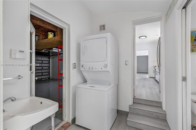 washroom with stacked washer and clothes dryer, sink, and light hardwood / wood-style flooring