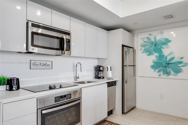 kitchen with stainless steel appliances, white cabinetry, and sink