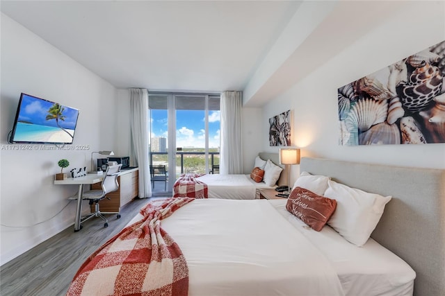 bedroom featuring wood-type flooring, access to exterior, and floor to ceiling windows