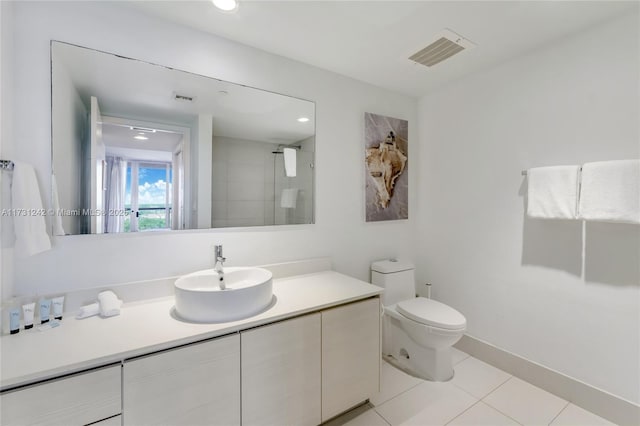 bathroom with vanity, tile patterned flooring, toilet, and tiled shower