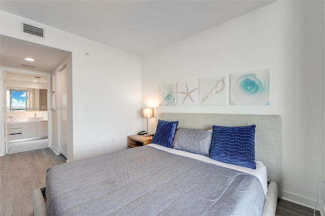 bedroom featuring ensuite bath and hardwood / wood-style flooring