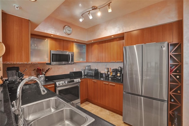 kitchen featuring sink, stainless steel appliances, dark stone counters, and light tile patterned flooring