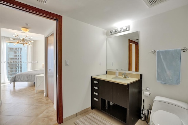 bathroom featuring tile patterned flooring, vanity, a chandelier, and toilet