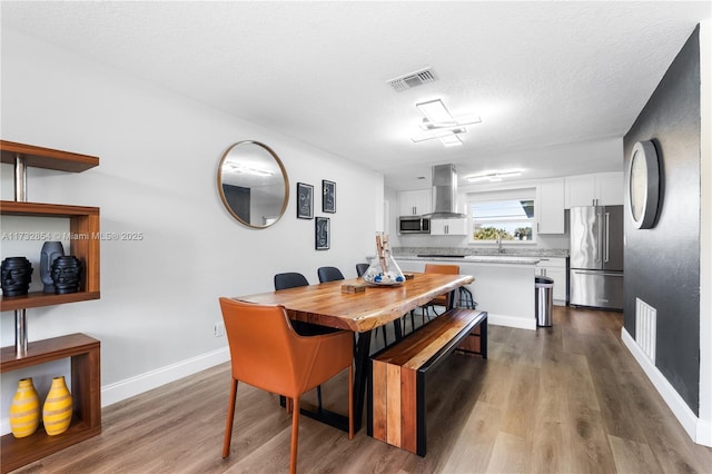 dining area with hardwood / wood-style flooring, sink, and a textured ceiling