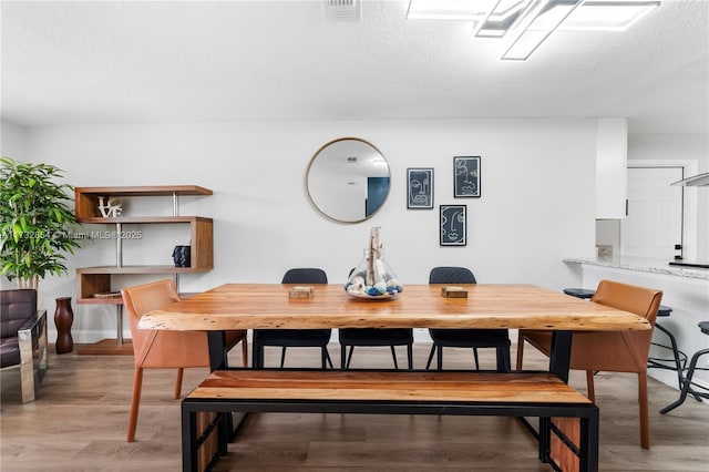 dining space featuring light hardwood / wood-style flooring and a textured ceiling