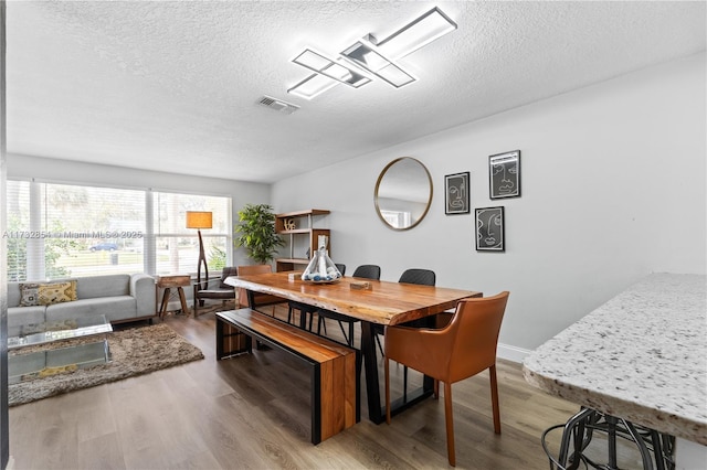 dining room with hardwood / wood-style flooring and a textured ceiling