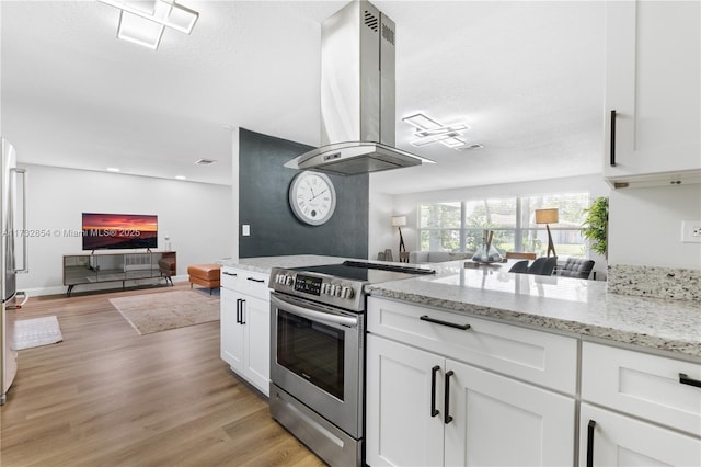 kitchen with light stone counters, island range hood, light wood-type flooring, electric stove, and white cabinets