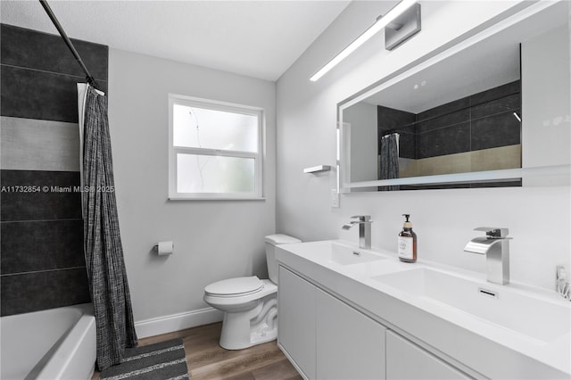 full bathroom with hardwood / wood-style flooring, vanity, shower / bath combination with curtain, and toilet