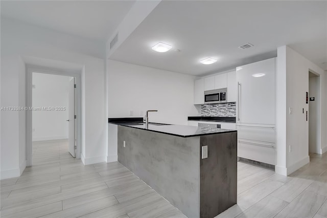 kitchen with sink, white cabinets, backsplash, and kitchen peninsula