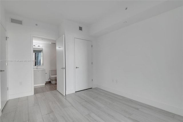 unfurnished bedroom featuring connected bathroom and light hardwood / wood-style flooring