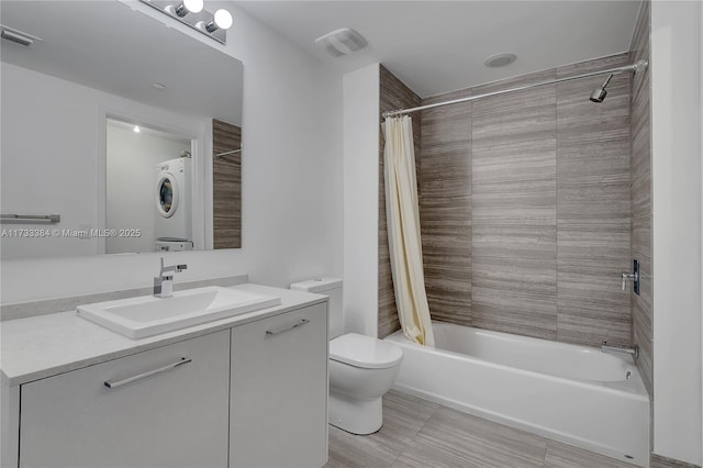 full bathroom with shower / tub combo with curtain, stacked washer and dryer, tile patterned flooring, vanity, and toilet