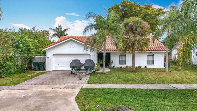 mediterranean / spanish-style house featuring a garage and a front lawn