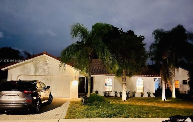 view of front of property featuring a garage, central AC unit, and a front lawn