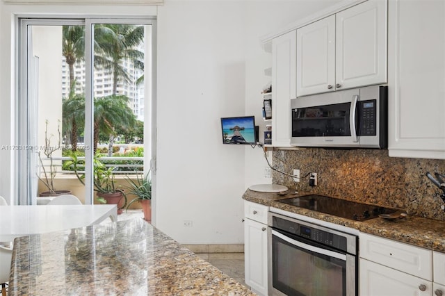 kitchen with decorative backsplash, appliances with stainless steel finishes, white cabinets, and dark stone counters