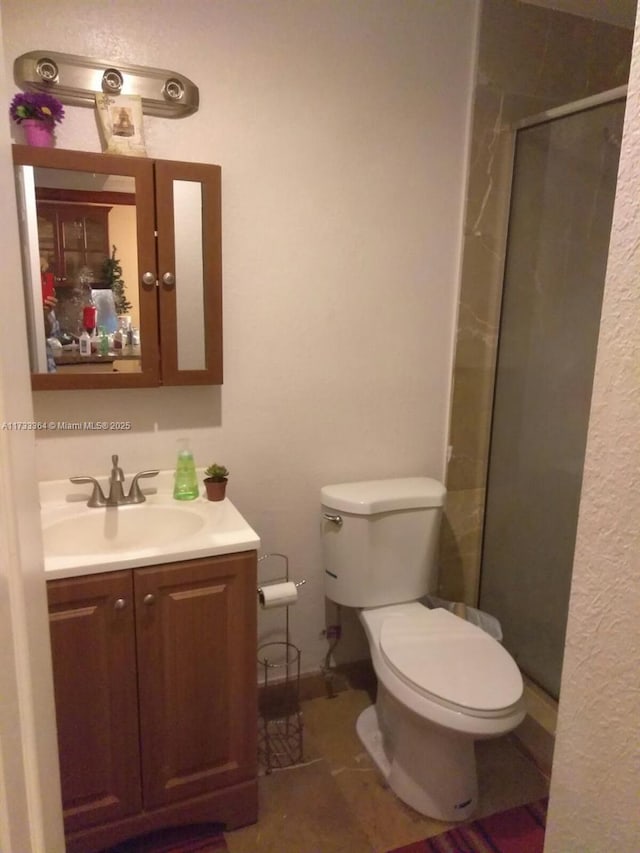 bathroom with tile patterned floors, vanity, toilet, and a shower with shower door