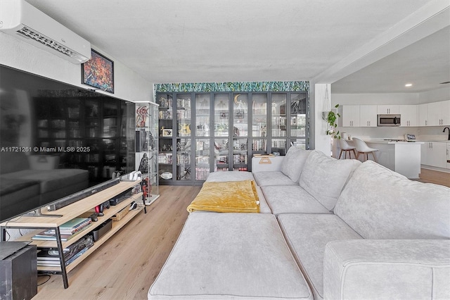 living room with sink, a wall mounted AC, and light wood-type flooring