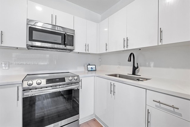 kitchen with white cabinetry, sink, light hardwood / wood-style flooring, and appliances with stainless steel finishes