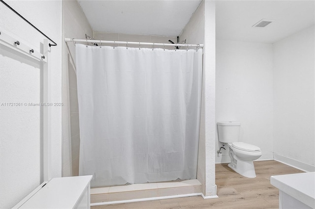 bathroom featuring wood-type flooring, toilet, and a shower with shower curtain