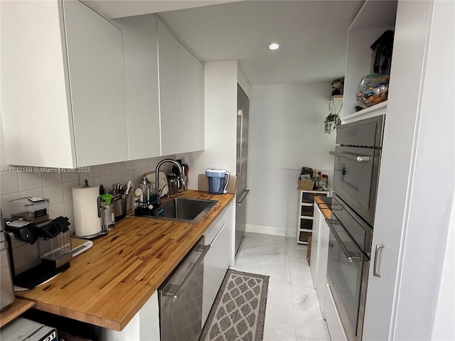 kitchen with sink, wooden counters, white cabinets, decorative backsplash, and stainless steel appliances