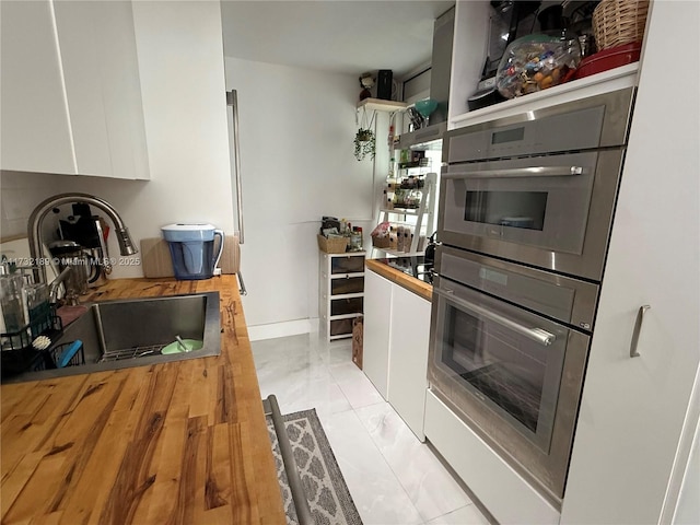 kitchen featuring stainless steel double oven, sink, and white cabinets