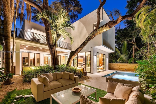 exterior space featuring a hot tub, a patio, a balcony, and an outdoor hangout area