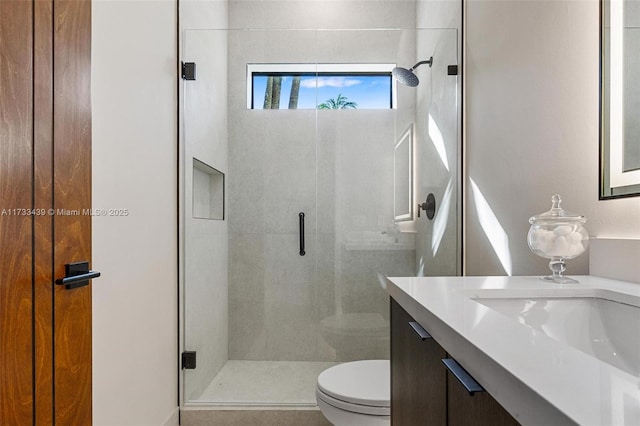 bathroom with a shower with door, vanity, and toilet