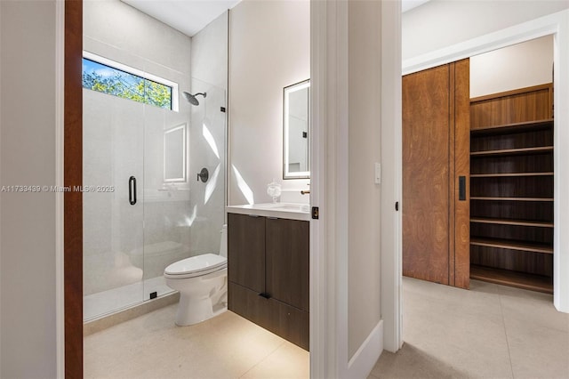 bathroom featuring vanity, a shower with shower door, tile patterned floors, and toilet