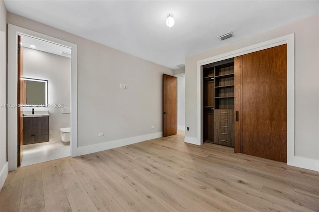 unfurnished bedroom with connected bathroom, a closet, and light wood-type flooring