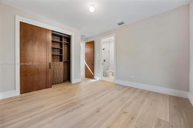 unfurnished bedroom featuring connected bathroom, a closet, and light wood-type flooring