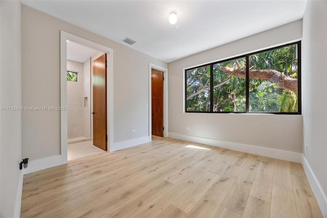 unfurnished bedroom with connected bathroom and light wood-type flooring