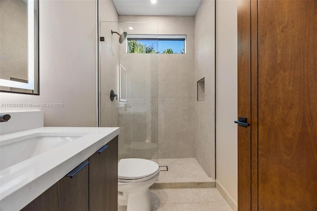 bathroom featuring tile patterned floors, vanity, toilet, and a tile shower