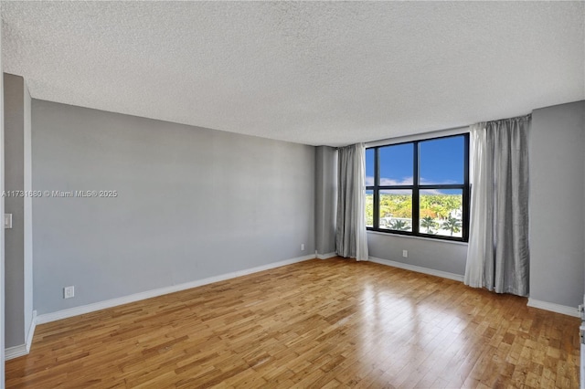 spare room with a textured ceiling and light wood-type flooring