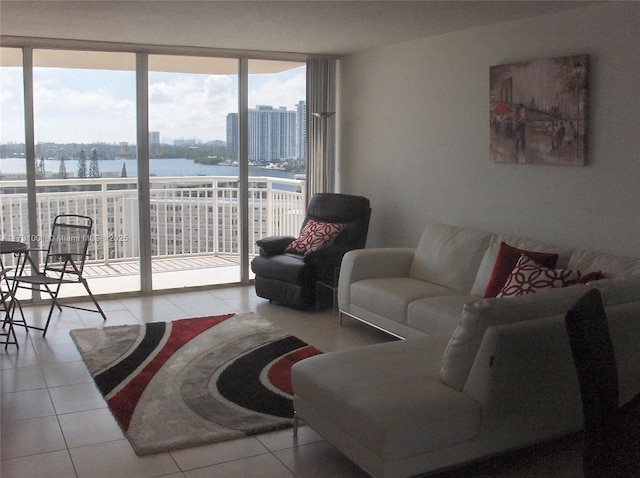 living room featuring light tile patterned floors, a wall of windows, and a water view