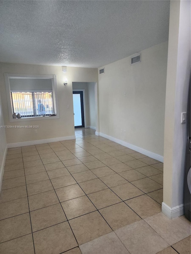 empty room featuring light tile patterned floors and a textured ceiling