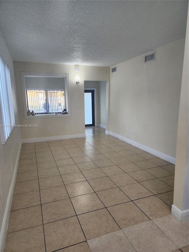 tiled empty room with a textured ceiling