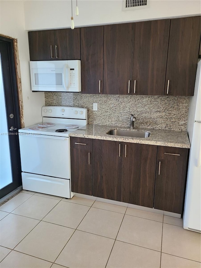 kitchen featuring white appliances, sink, dark brown cabinets, and light tile patterned floors