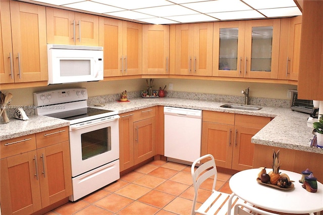 kitchen featuring sink, light stone counters, white appliances, and light tile patterned floors